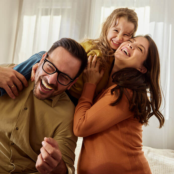 Smiling parents laughing and playing with child indoors