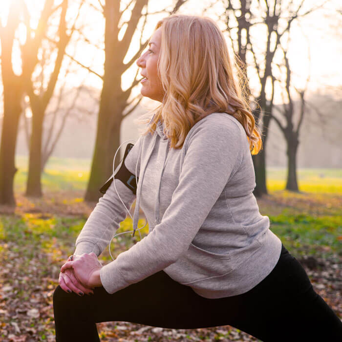 Mature woman exercising in park, stretching